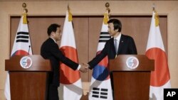 Menteri Luar Negeri Korea Selatan Yun Byung-se, kanan, berjabat tangan dengan Menteri Luar Negeri Jepang Fumio Kishida setelah konferensi pers gabungan di Kementerian Luar Negeri di Seoul, Korea Selatan, Senin, 28 Desember 2015.