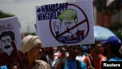 A supporter of Venezuela's President Nicolas Maduro holds a placard depicting U.S. President Donald Trump during a rally in Caracas, Sept. 19, 2017.