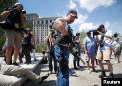 Steve Thacker carrying a rifle and a handgun is surrounded by news media in a public square in Cleveland, Ohio, July 17, 2016.