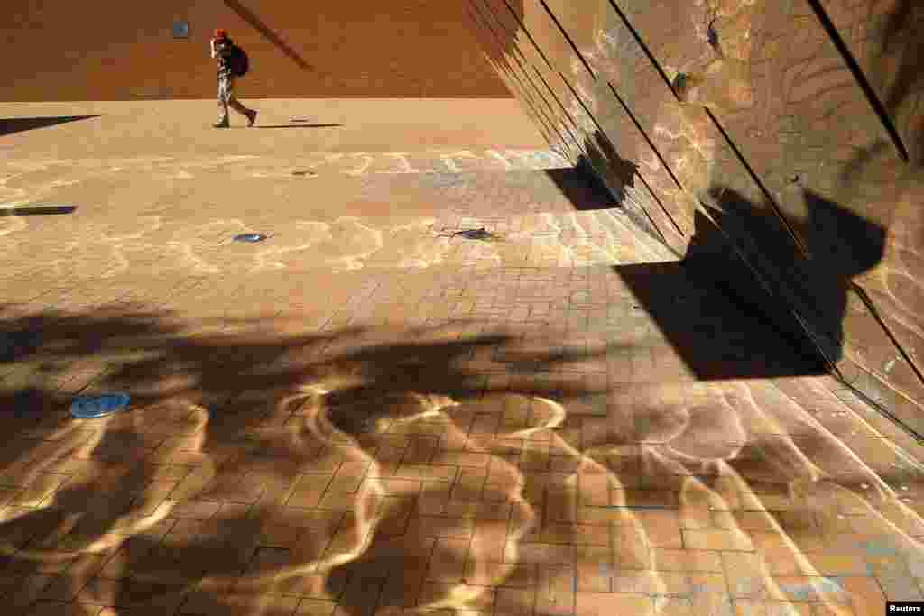 A woman walks outside the Stat Building at the Massachusetts Institute of Technology on a sunny fall day in Cambridge. 