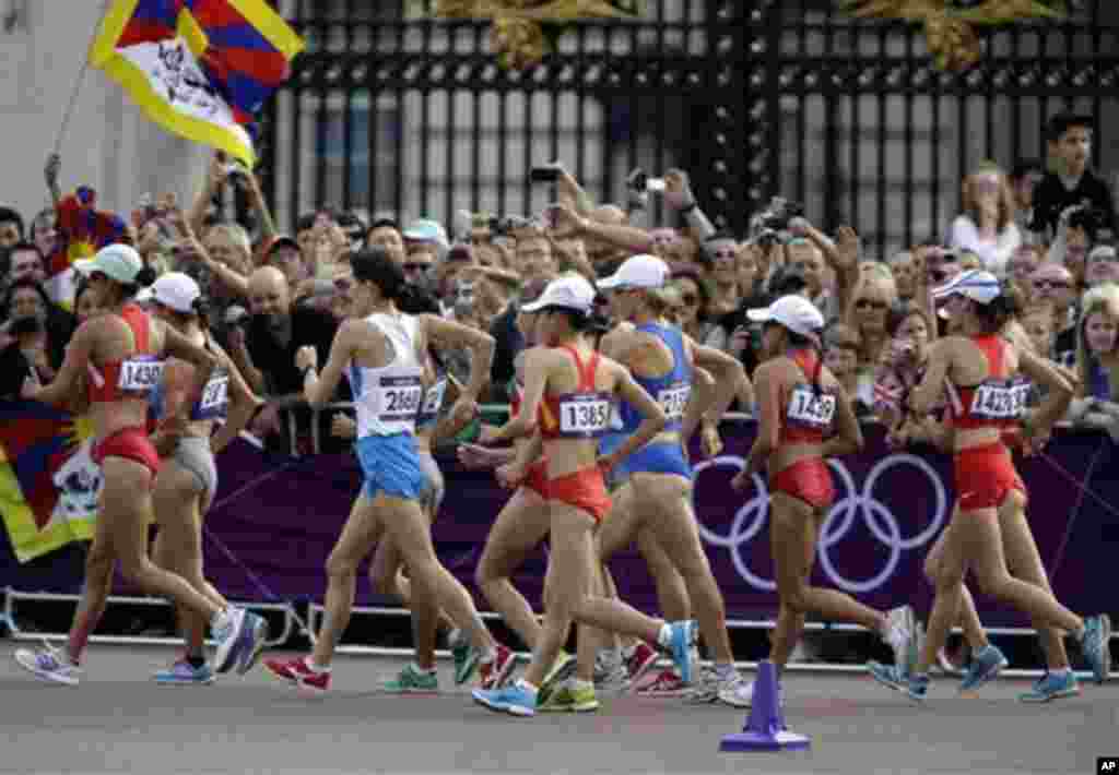 A Tibetan flag, left, pass Buckingham Palace at the 2012 Summer Olympics, Saturday, Aug. 11, 2012, in London.