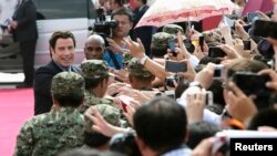 American actor John Travolta (L) shakes hands with fans as he arrives for the launch ceremony of the Qingdao Oriental Movie Metropolis on the outskirts of Qingdao, China, September 22, 2013.