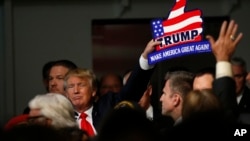 Republican presidential candidate, businessman Donald Trump, holds one of his signs after a rally coinciding with Pearl Harbor Day at Patriots Point aboard the aircraft carrier USS Yorktown in Mt. Pleasant, S.C., Monday, Dec. 7, 2015.