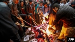 Iranians pour fuel on US flags set aflame during an anti-US demonstration outside the former US embassy headquarters in the capital Tehran on May 9, 2018.