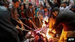 Manifestantes iraníes incendian banderas estadounidenses durante una protesta frente al edificio de la antigua embajada de EE.UU. en Teherán. Mayo 9, 2018.