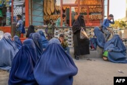 Sejumlah perempuan bercadar menunggu di depan toko roti untuk mendapatkan donasi roti di Kabul. (Foto: AFP)