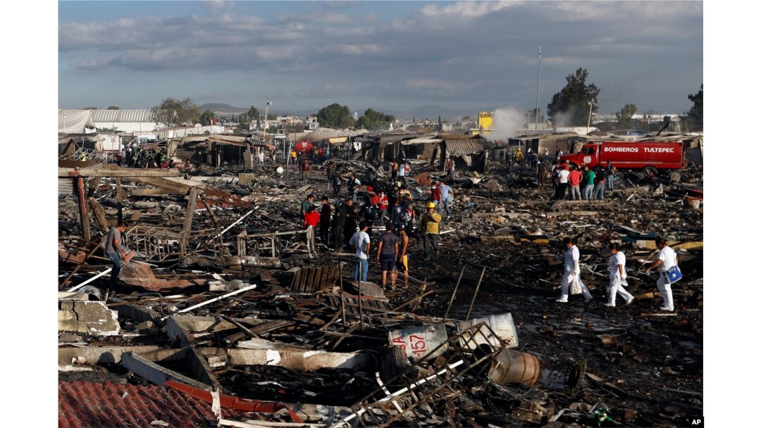 Firefighters and rescue workers walk through the scorched ground of Mexico's best-known fireworks market after an explosion explosion ripped through it, in Tultepec, Mexico, Dec. 20, 2016.