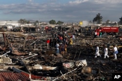 Firefighters and rescue workers walk through the scorched ground of Mexico's best-known fireworks market after an explosion explosion ripped through it, in Tultepec, Mexico, Dec. 20, 2016.