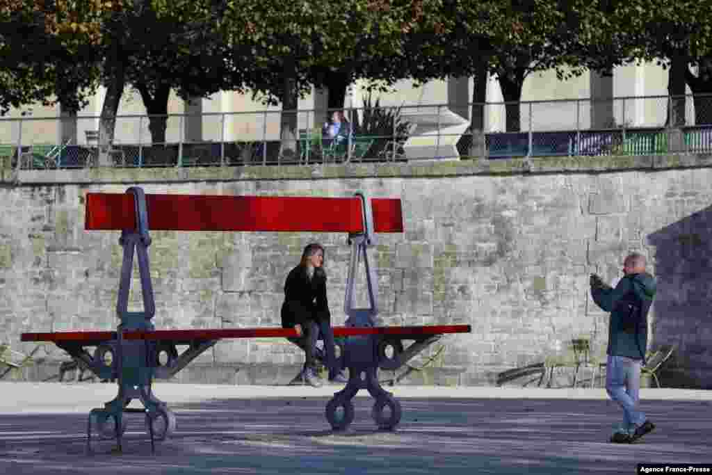 A woman sits on a piece of artwork, &quot;Double Banc,&quot; by French artist Lilian Bourgeat, at the French International Contemporary Art Fair, in the Jardin des Tuileries in Paris, France.