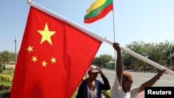FILE - Workers put up flags a day before Chinese President Xi Jinping's visit to Myanmar in Naypyitaw, Myanmar, January 16, 2020. 