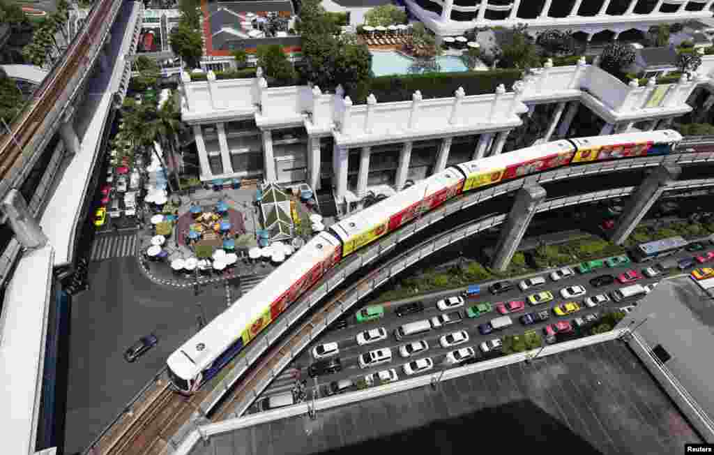 A skytrain passes over vehicles on the road in Bangkok, Thailand..