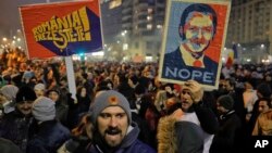 People hold posters depicting the leader of the ruling Social Democratic party, Liviu Dragnea, the other reading "Romania-Wake Up" during a protest in Bucharest, Romania, Feb. 1, 2017.