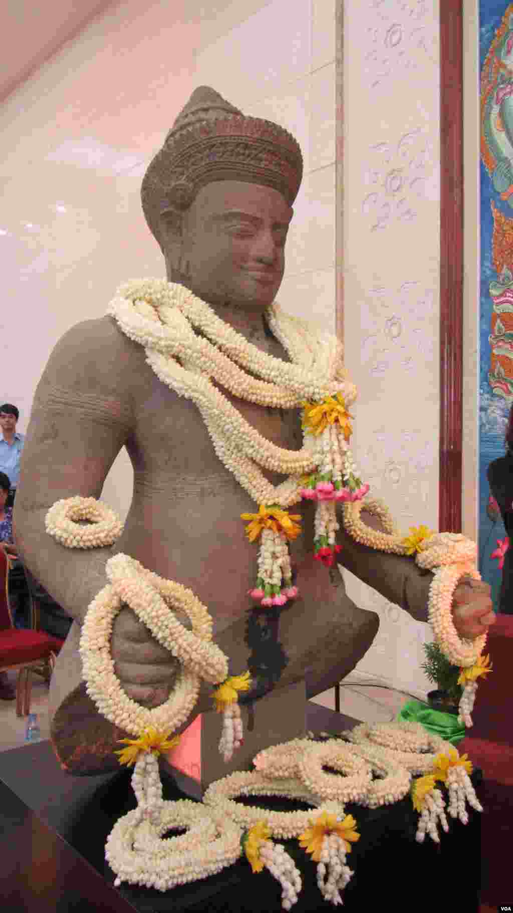 A 10th century Cambodian sandstone statue that was returned from the United States is draped with flowers at the Council of Ministers in Phnom Penh, June, 3, 2014. (VOA Khmer)