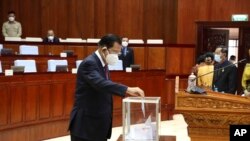 In this photo released by Cambodia's National Assembly, Cambodian Prime Minister Hun Sen drops a ballot into a box in the National Assembly hall in Phnom Penh, Cambodia, Monday, Oct. 25, 2021. (Cambodia's National Assembly via AP)