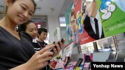 한국 서울에서 전시된 스마트폰을 만져보는 소비자들. (자료사진)