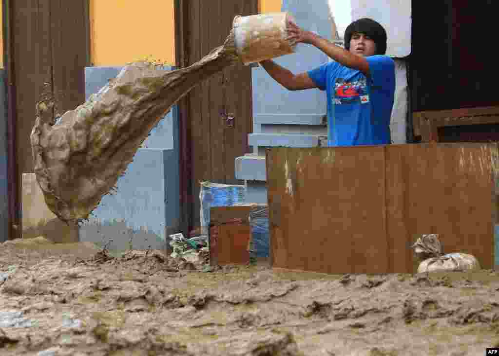 Seorang warga Peru membuang air banjir yang memasuki rumahnya di kota Trujillo, Peru utara.