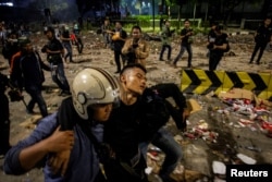 Seorang polisi membawa rekannya yang terluka dalam aksi unjuk rasa 23 Mei 2019 di Jakarta (Foto: Antara).