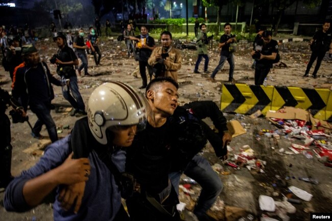 Seorang polisi yang cedera dievakuasi oleh rekannya setelah aparat keamanan bentrok dengan para pengunjuk rasa di Jakarta, 23 Mei 2019. (Foto: Antara Foto via Reuters)