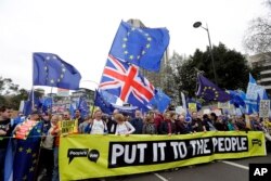 FILE - Demonstrators hold a banner during a Peoples Vote anti-Brexit march in London, March 23, 2019.