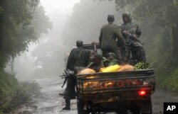 FILE - Congolese M23 rebels carry goods in the back of a truck near the Congo-Uganda border town of Bunagana, DRC, Dec. 5, 2012.