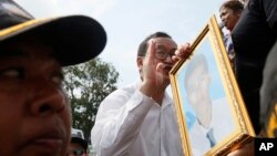 Opposition leader Sam Rainsy, center, of Cambodia National Rescue Party, speaks to garment workers near Freedom Park as his party member holds a portrait photo of a factory worker who was shot dead earlier this year, in Phnom Penh, Cambodia, Thursday, May 1, 2014. Security forces have beaten demonstrators after a May day rally held in defiance of a government ban on public protests in the Cambodian capital. Nearly 1,000 factory workers and supporters of the opposition Cambodia National Rescue Party had gathered on the streets outside the city's Freedom Park, which had been barred to demonstrators and sealed off. (AP Photo)