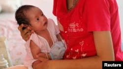 FILE - An unnamed teenager holds her son at the Association for the Promotion of the Status of Women in Bangkok.