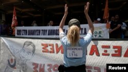 A municipal police officer applauds during a rally against public sector layoffs, which the government has promised its international lenders in exchange for bailout funds, Athens, Greece, July 12, 2013. 