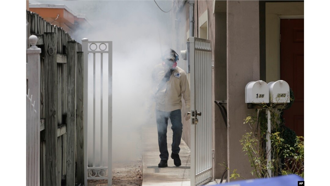 A Miami-Dade County mosquito control worker sprays around a home in the Wynwood area of Miami, Aug. 1, 2016.