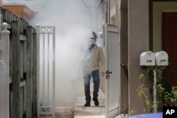 A Miami-Dade County mosquito control worker sprays around a home in the Wynwood area of Miami, Aug. 1, 2016.