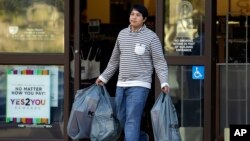 FILE - A man carries bags out of a department store, in Alameda, California, Dec. 17, 2015. Stronger-than-expected consumer spending helps ease fears of a U.S. recession.