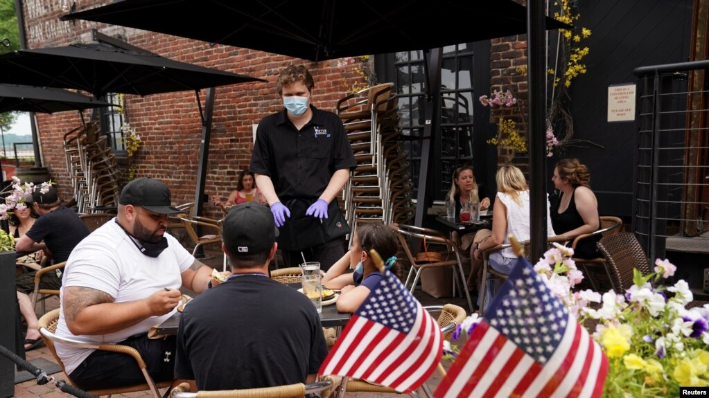 Nhân viên đeo khẩu trang phục vụ khách ngồi bên ngoài tại một nhà hàng ở thành phố Alexandria, Virginia, khi khu vực phía bắc của bang này cho phép mở cửa lãi, ngày 29 tháng 5, 2020. 