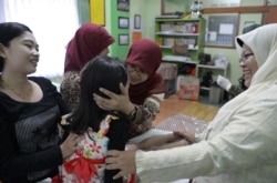 Seorang ibu (kiri) dan bidan mengucapkan selamat kepada Kania, 4 tahun (tengah), usai menjalani sunat perempuan di Bandung, Jawa Barat, 10 Februari 2021. (Foto: Adek Berry/AFP)