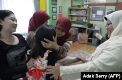 Seorang ibu (kiri) dan bidan mengucapkan selamat kepada Kania, 4 tahun (tengah), usai menjalani sunat perempuan di Bandung, Jawa Barat, 10 Februari 2021. (Foto: Adek Berry/AFP)