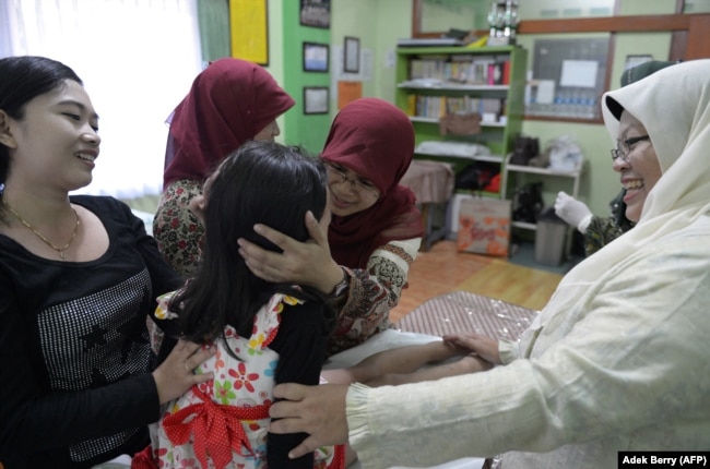 Seorang ibu (kiri) dan bidan mengucapkan selamat kepada Kania, 4 tahun (tengah), usai menjalani sunat perempuan di Bandung, Jawa Barat, 10 Februari 2021. (Foto: Adek Berry/AFP)
