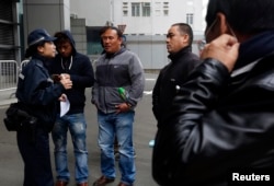 A policewoman talks to a group of Nepalese men, who have invested in bitcoin, outside the police headquarters in Hong Kong Feb. 11, 2015. Hong Kong lawmakers at that time urged authorities to ban bitcoin as more than 25 people flocked to police headquarters to complain over a scam involving the digital currency that media estimate could have duped investors of up to $387 million.