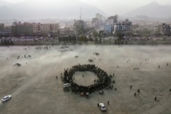 Para penonton berkerumun membuat lingkaran, saat menonton adu gulat tradisional di taman Chaman-e-Hozori, di pusat kota Kabul, Afghanistan, Jumat, 3 Desember 2021.