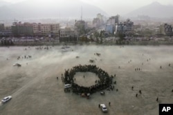 Para penonton berkerumun membuat lingkaran, saat menonton adu gulat tradisional di taman Chaman-e-Hozori, di pusat kota Kabul, Afghanistan, Jumat, 3 Desember 2021.
