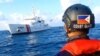菲律宾海上警卫队员驾驶橡皮艇在南中国海惠特森礁附近注视着菲律宾海上警卫舰。（2021年4月13日）