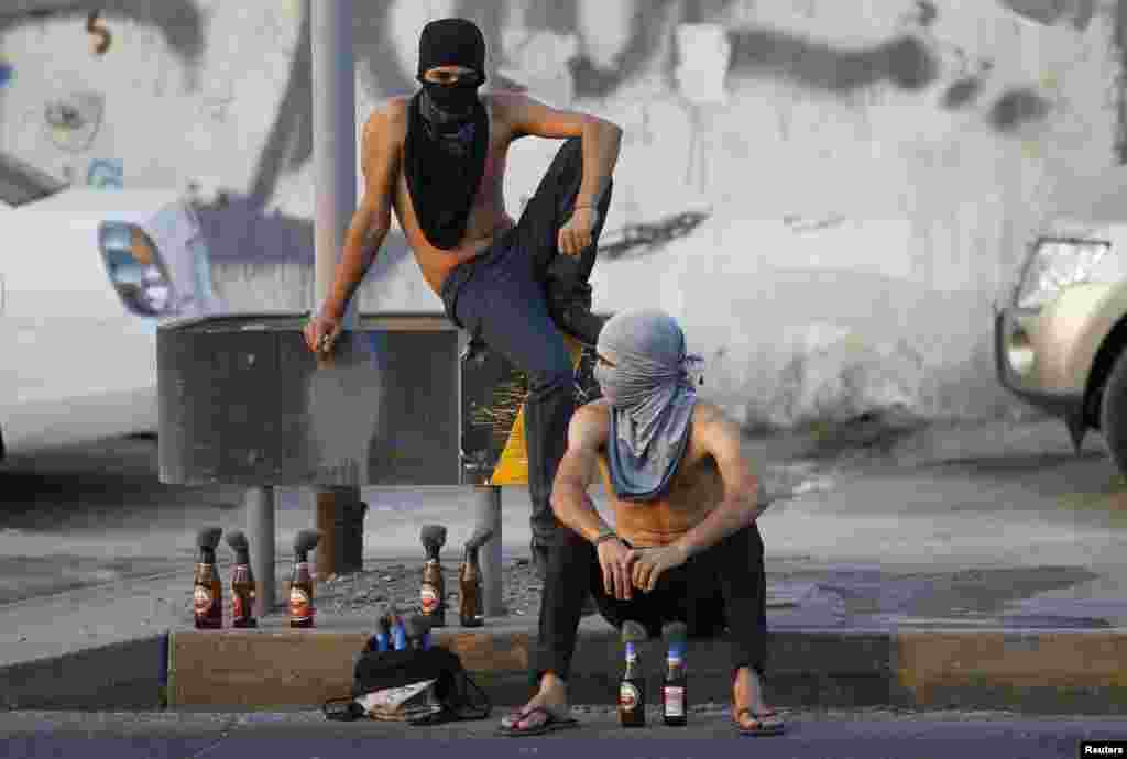 Anti-government protesters sit by the roadside with molotov cocktails as they wait for others to join during clashes after the Ashura procession in the village of Sanabis west of Manama, Bahrain.