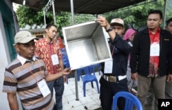 FILE - Electoral workers show an empty box before the opening station for voters during the gubernatorial election in Jakarta, Indonesia, Feb. 15, 2017.