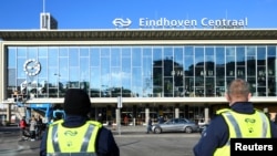 Petugas keamanan berdiri di seberang stasiun kereta pusat pasca kerusuhan terkait jam malam di Eindhoven, Belanda 25 Januari 2021. (REUTERS / Piroschka van de Wouw)