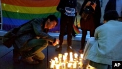 A man lights a candle during a spontaneous vigil to remember those slain and wounded at an Orlando nightclub, in Paris, France, June 12, 2016.
