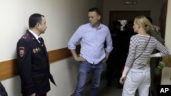 2017年6月12日，俄罗斯反对派领袖纳瓦尔尼(中)和他的妻子喻立亚(Yulia)在莫斯科一场法院听证会开始前交谈。