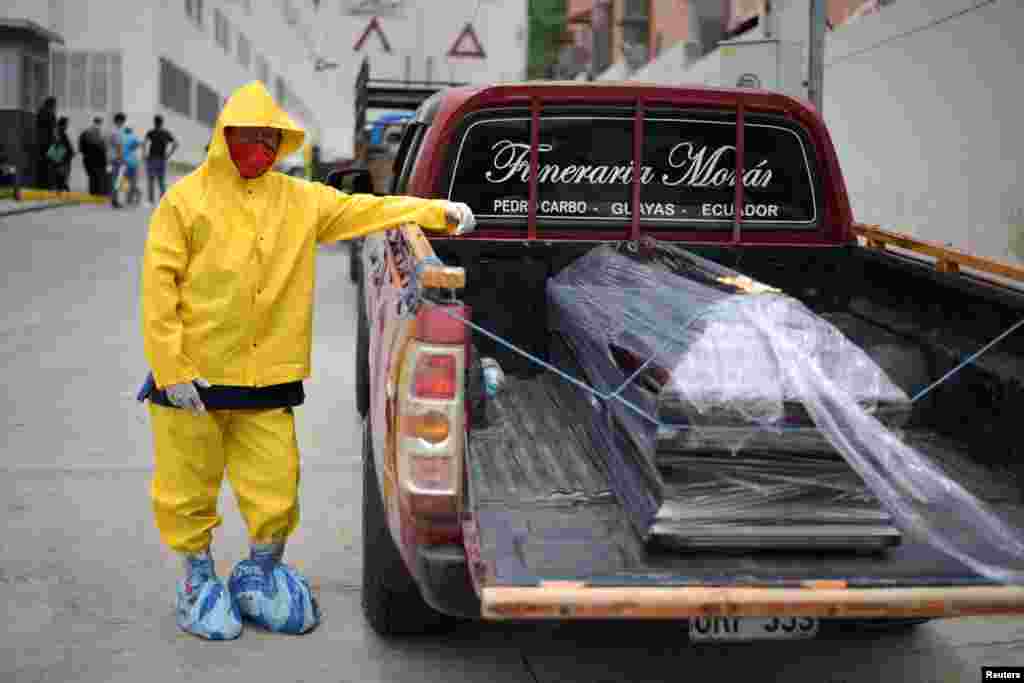 Un trabajador de una funeraria, con traje de protección, espera con un ataúd en una camioneta afuera del hospital Los Ceibos el 1 de abril de 2020.