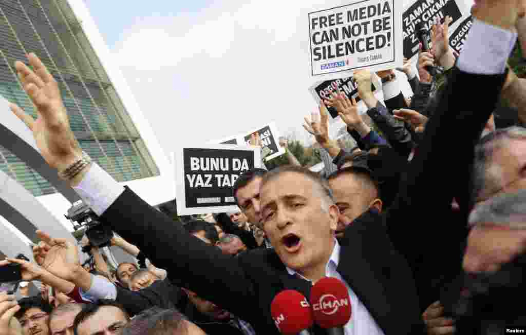 Zaman editor-in-chief Ekrem Dumanli, surrounded by his colleagues and plainclothes police officers (C), reacts as he leaves the headquarters of Zaman daily newspaper in Istanbul. Turkish police raided media outlets close to a U.S.-based Muslim cleric and detained 24 people including top executives and ex-police chiefs in operations against what President Tayyip Erdogan calls a terrorist network conspiring to topple him.