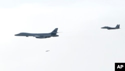 A U.S. Air Force B-1B Lancer bomber, left, drops a bomb over the Korean Peninsula, South Korea, July 8, 2017, in this photo provided by South Korea Defense Ministry. Two U.S. bombers flew to the Korean Peninsula to join fighter jets from South Korea and Japan for a practice bombing run as part of a training mission in response to North Korea's ballistic missile and nuclear programs, officials said Friday.