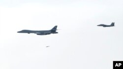 韩国国防部提供的图片显示，一架美国空军B-1B“枪骑兵”战略轰炸机（左一）往朝鲜半岛投下一颗炸弹。（2017年7月8日）