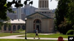 FILE - In this file photo from June 7, 2019, a man walks by Hamerschlag Hall on the Carnegie Mellon University campus in Pittsburgh. Colleges in the U.S. have seen a sharp enrollment drop among international students in the fall of 2020. University admini