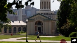 FILE - In this file photo from June 7, 2019, a man walks by Hamerschlag Hall on the Carnegie Mellon University campus in Pittsburgh. Colleges in the U.S. have seen a sharp enrollment drop among international students in the fall of 2020. 