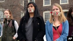 Brown University senior Maahika Srinivasan, center, of New Delhi, India, stands with senior Jeanette Sternberg Lamb, right, of Asheville, N.C., on the campus in Providence, R.I., where they organized a march to protest how the college handled recent sexua